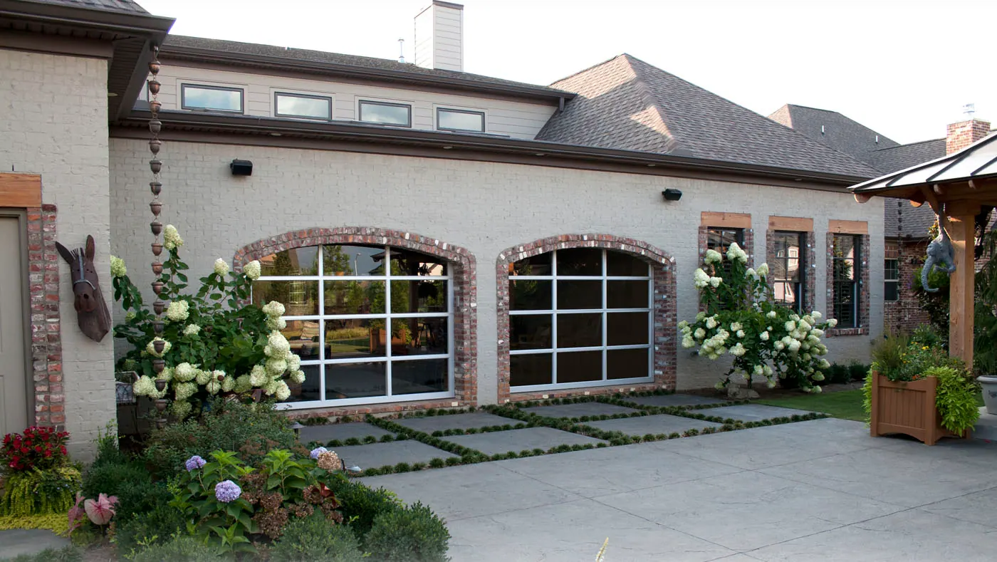 Safe-Way Ventana full-view aluminum garage doors on a white brick home, wide front elevation