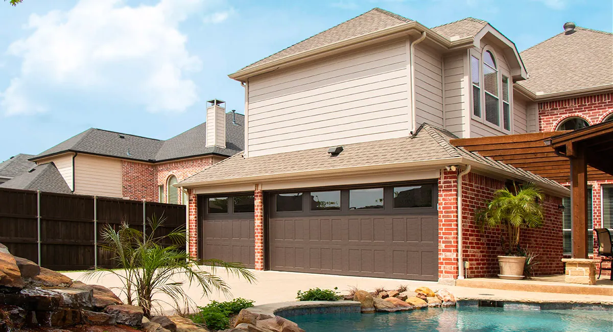 back of home with brown garage door and a pool