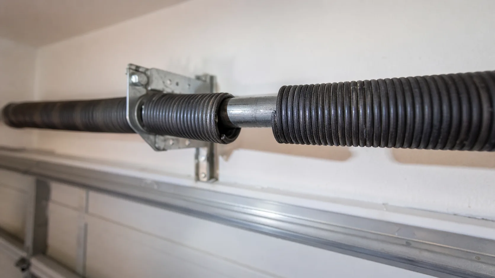 Close-up of a snapped torsion spring on a residential garage door showing the distinctive 2-inch gap in the coils where it has separated — the classic visual sign of a broken garage door spring in an Arizona home